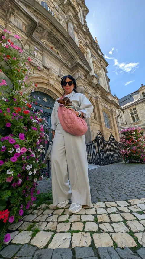 Celine in de roze draagtas voor een barokke kerkgevel met bloemen