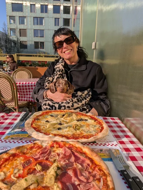 Celine op schoot op een terras bij twee pizza’s