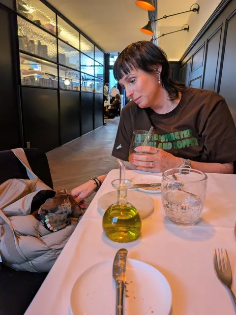 Celine in haar tas aan tafel in een restaurant