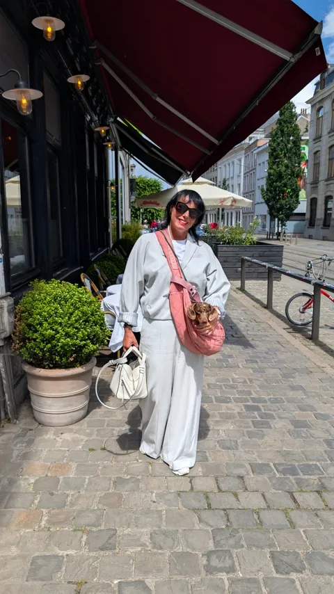 Celine in de roze draagtas langs een terras met een rode luifel