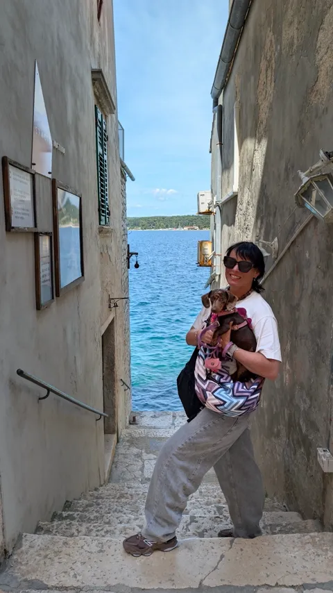 Celine in de draagtas op een trap tussen oude huizen in Rovinj die uitkomt op de zee