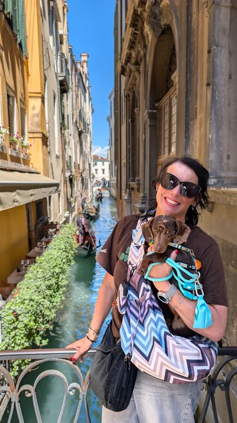 Celine in de draagtas boven een gracht met gondels in Venetië