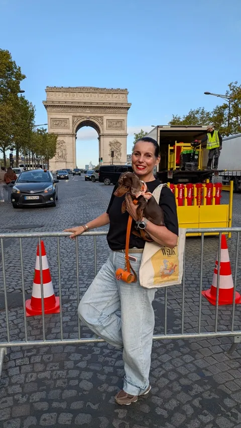 Celine in de armen van haar baasje voor de Arc de Triomphe, met de tas van de Sausage Walk