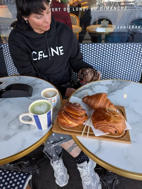 Celine op het terras van een bakkerij, met croissants en een matcha latte