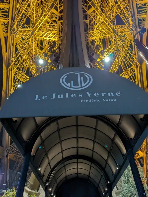 De ingang van restaurant Le Jules Verne in de verlichte Eiffeltoren