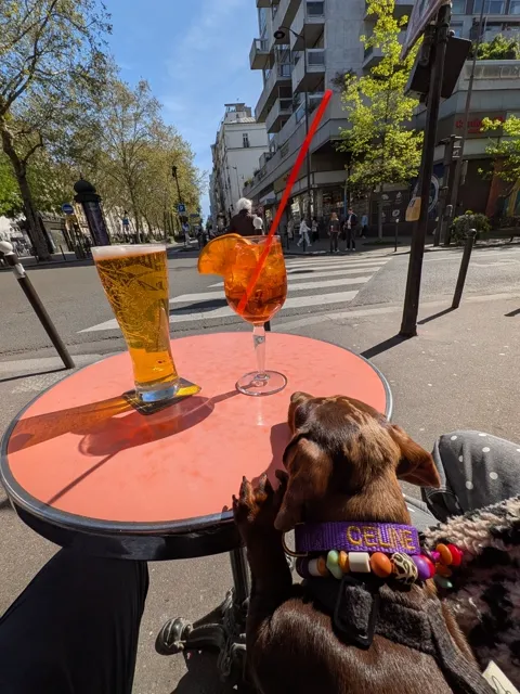 Celine aan een rond terrastafeltje met een biertje en een spritz
